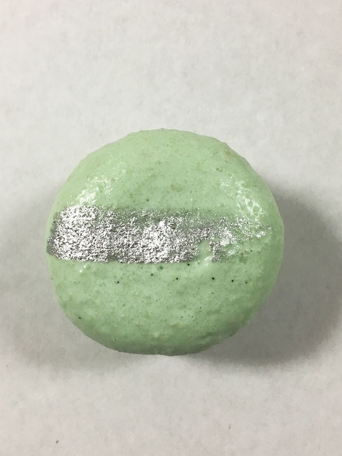 A green-colored macaron with a silver streak on its surface.