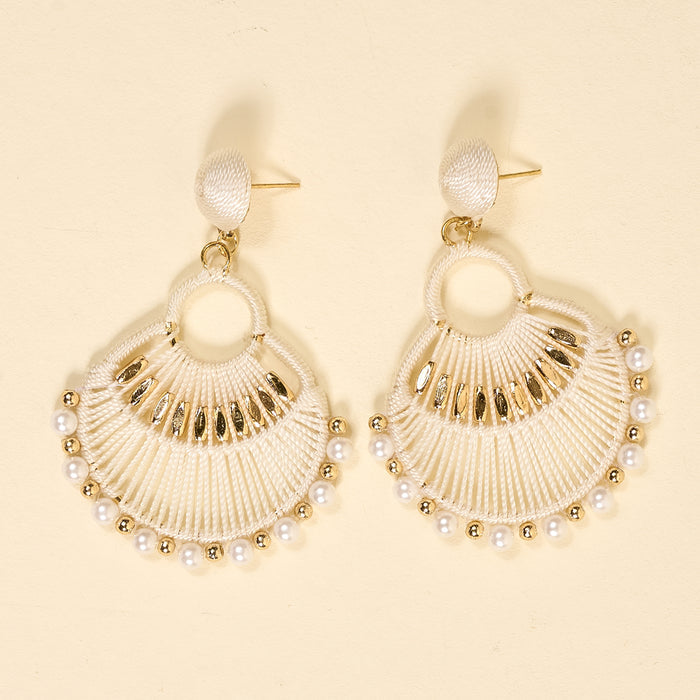 The Darling Effect's White Paloma Drop Earrings feature a round, fan-shaped boho design with white thread, gold accents, and small white pearls along the bottom edge, shown on a light beige background.