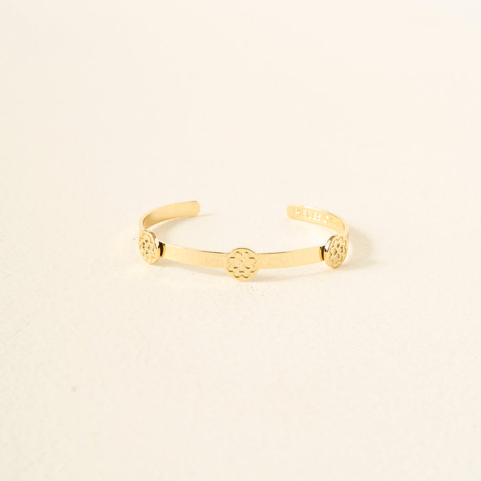The Darling Effect's You Are Loving Skinny Stacker Bracelet is an adjustable 14k gold plated cuff with three small round floral motifs, elegantly displayed on a light neutral background.