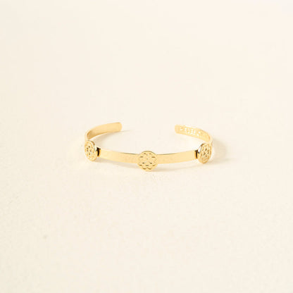 The Darling Effect's You Are Loving Skinny Stacker Bracelet is an adjustable 14k gold plated cuff with three small round floral motifs, elegantly displayed on a light neutral background.