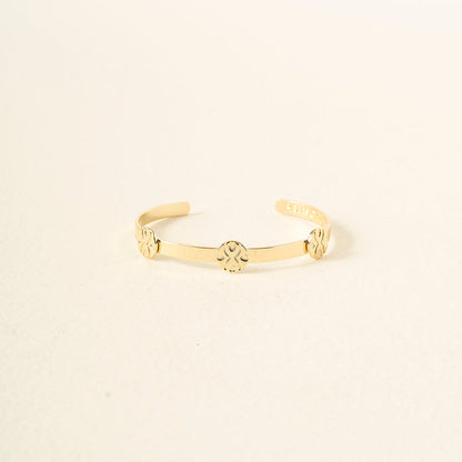 The Darling Effect's "You Are Loyal" Skinny Stacker Trait Bracelet is a 14k gold plated adjustable cuff, engraved with three floral designs, shown on a light cream background—a gift-ready and elegant accessory.
