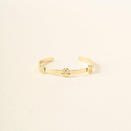 The Darling Effect's "You Are Loyal" Skinny Stacker Trait Bracelet is a 14k gold plated adjustable cuff, engraved with three floral designs, shown on a light cream background—a gift-ready and elegant accessory.