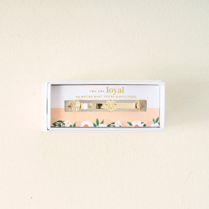 The Darling Effect's You Are Loyal Skinny Stacker Trait Bracelet comes in a gift-ready box with a floral border and the message: "You are loyal. No matter what, you're always there," displayed on a light, off-white surface.