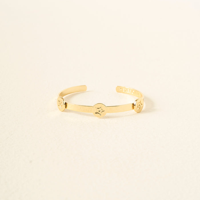 The Darling Effect’s You Are Passionate Skinny Stacker Bracelet is a 14k gold plated adjustable cuff with three round star-patterned accents, shown on a plain off-white background.