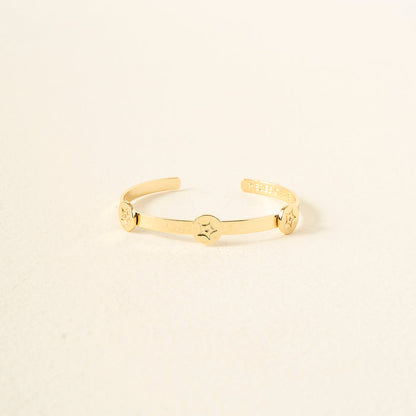 The Darling Effect’s You Are Passionate Skinny Stacker Bracelet is a 14k gold plated adjustable cuff with three round star-patterned accents, shown on a plain off-white background.