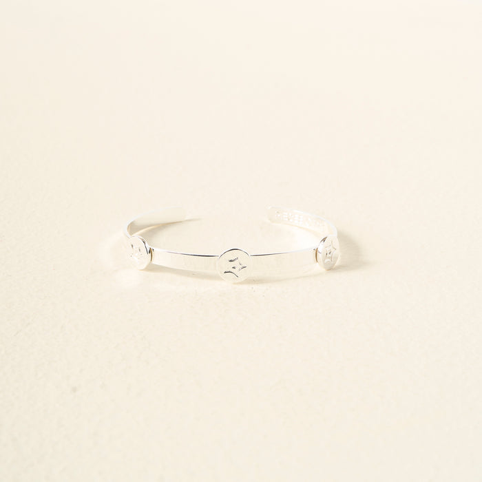 The Darling Effect’s You Are Passionate Skinny Stacker Bracelet—a silver adjustable cuff with three engraved smiley faces, shown on a light surface—makes gift-ready jewelry for any occasion.