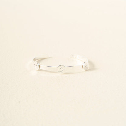 The Darling Effect’s You Are Passionate Skinny Stacker Bracelet—a silver adjustable cuff with three engraved smiley faces, shown on a light surface—makes gift-ready jewelry for any occasion.