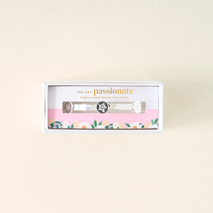 The Darling Effect’s You Are Passionate Skinny Stacker Bracelet is a silver adjustable cuff with star and heart designs, gift-boxed on a floral card reading “You are passionate. Pursue what makes you happy”—perfect for gifting.