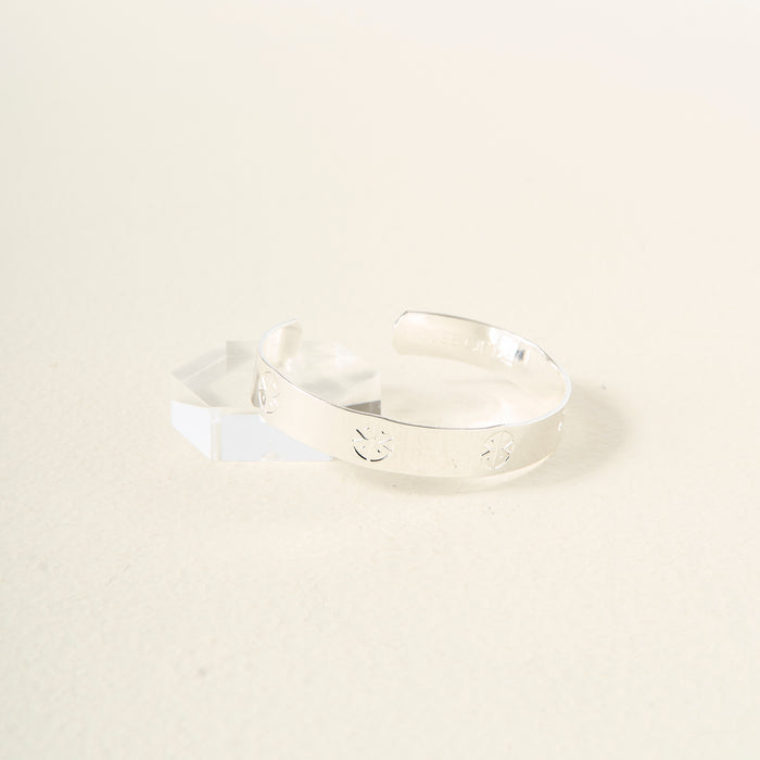 The Darling Effect’s You Are Strong Cuff Bracelet, crafted in shiny sterling silver with engraved star accents, rests on a white geometric block against a simple light background.